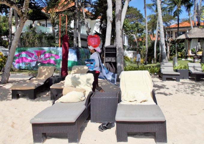 There are plenty of lounge chairs under palm trees for guests to relax in.
