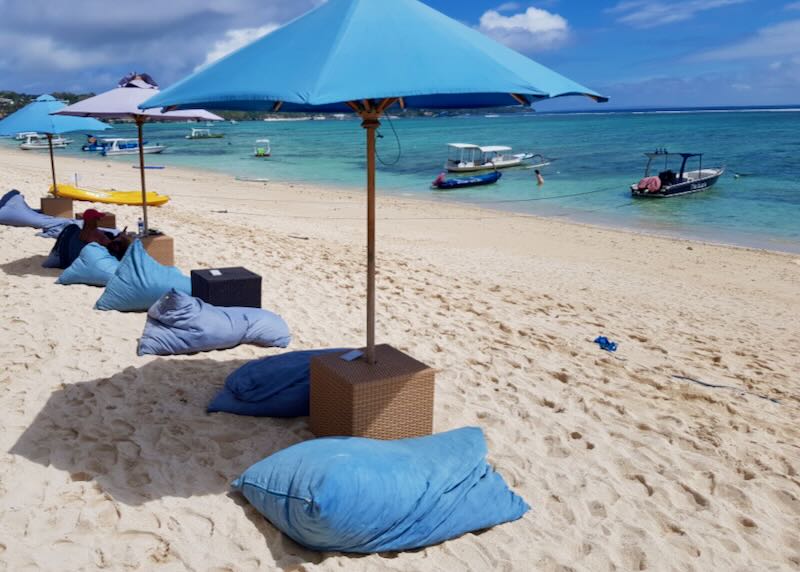Sun-bleached blue pillows and umbrellas line the beachfront at Indiana Kenanga Boutique Hotel & Spa in Nusa Lembongan Bali.