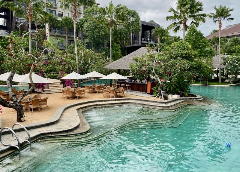 Tables and chairs sit beside the pool at Movenpick Resort & Spa in Jimbaran Bali.