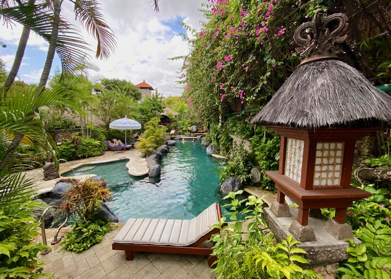 Guests lounge by a winding pool and hut at Poppies Bali in Kuta.
