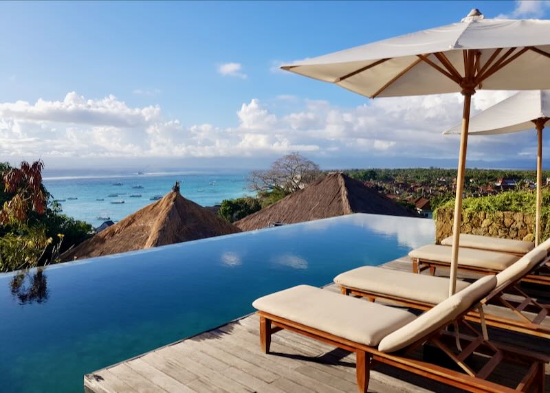 View of the straw rooftops and ocean from the infinity pool at the Tamarind Resort in Nusa Lembongan Bali.