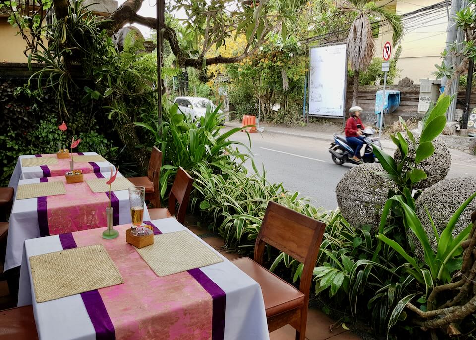 A scooter passes by empty tables at Ibu Rai restaurant.