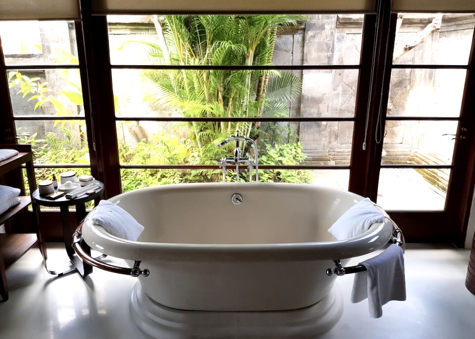An oval tub sits in the middle of the room with windows to the garden.