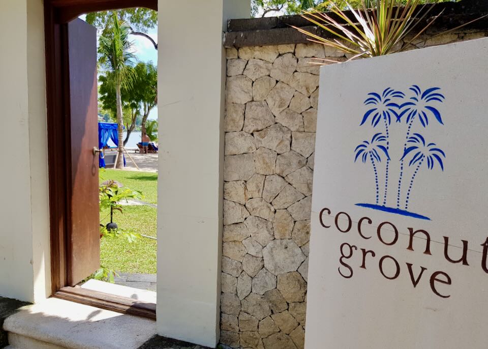 A stone wall entrance with a sign that reads, "Coconut Grove."
