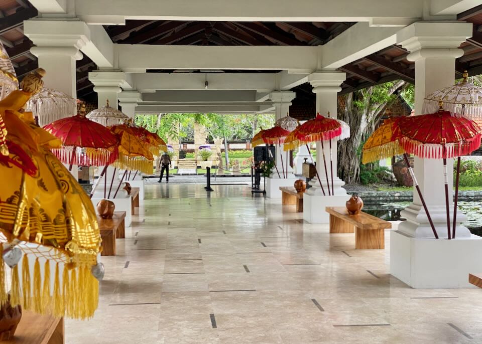 Colorful red and yellow umbrellas line the white marble walkway to the lobby.