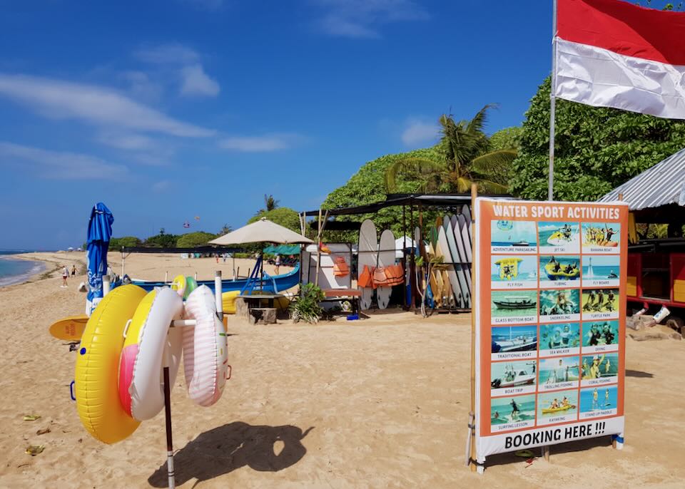 A sign reads, "water sports activities" next to surf boards, inner tubes, and life jackets.