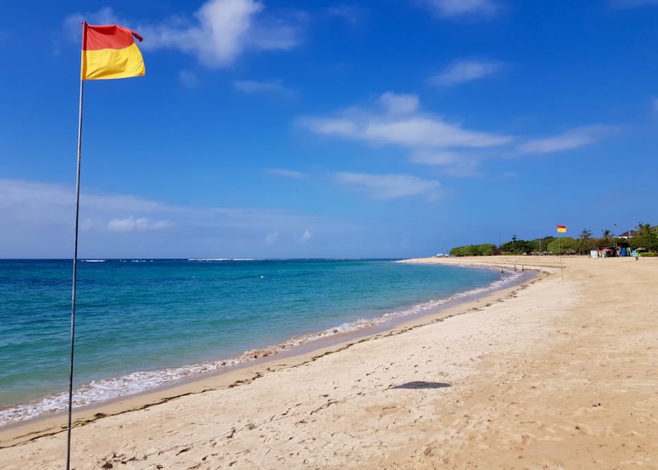 A red and yellow flag on the beach blows in the wind.