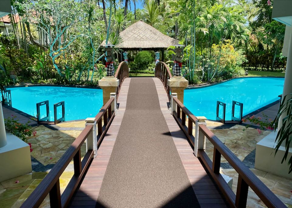 A wide walking path and bridge over the lagoon pool.