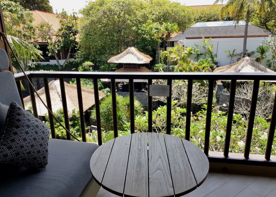 A table and chairs sit on a balcony overlooking the garden.
