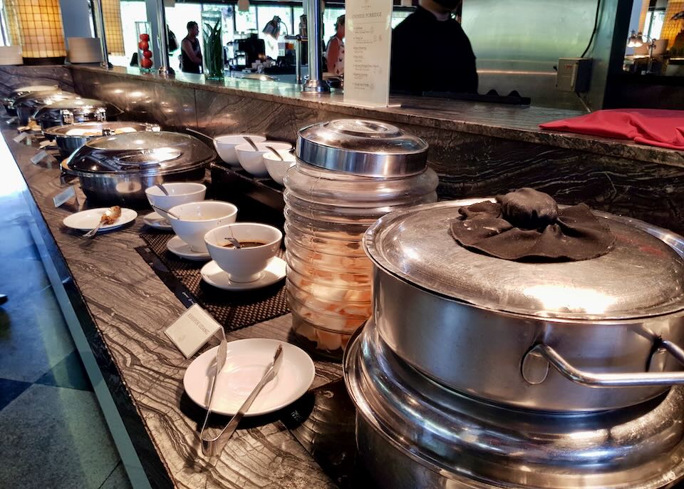 A row of pans and cups line a couner.