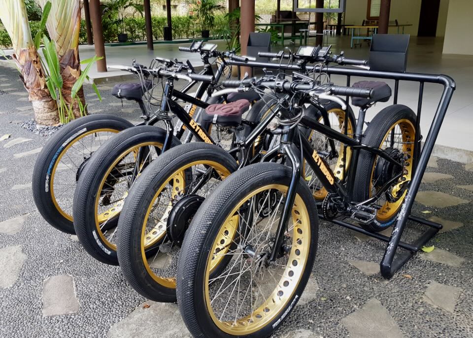 Several bikes sit on a sidewalk.