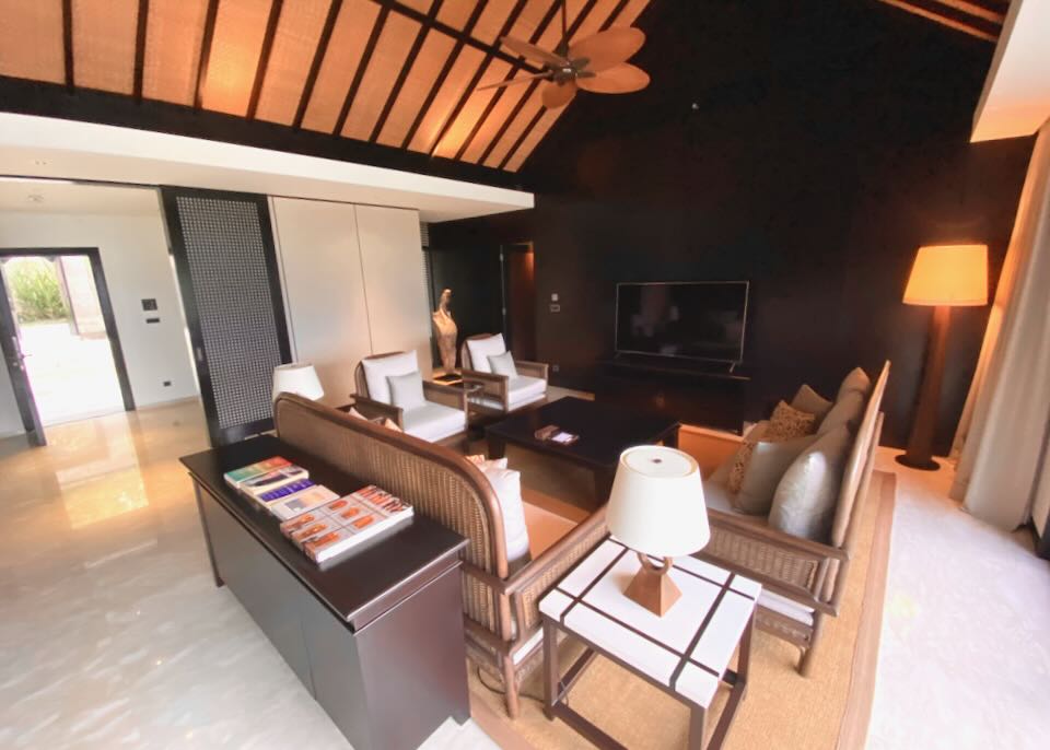 The high-ceiling living room has several couches and chairs and a tv.