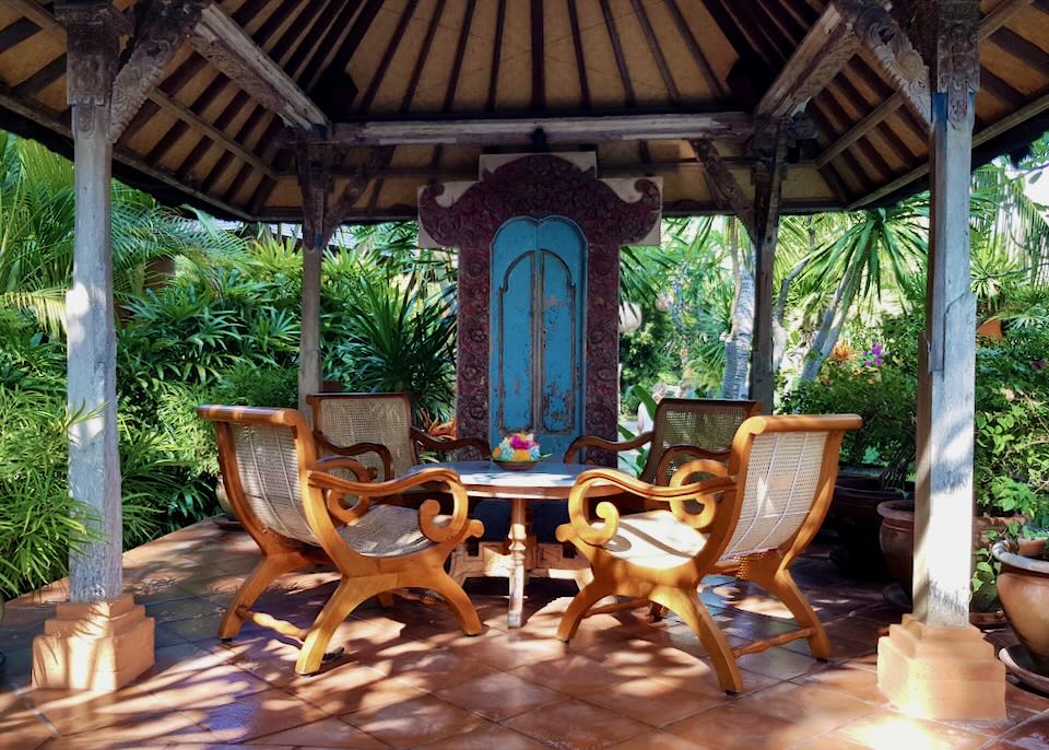 four ornate wood chairs sit under an outdoor canopy.