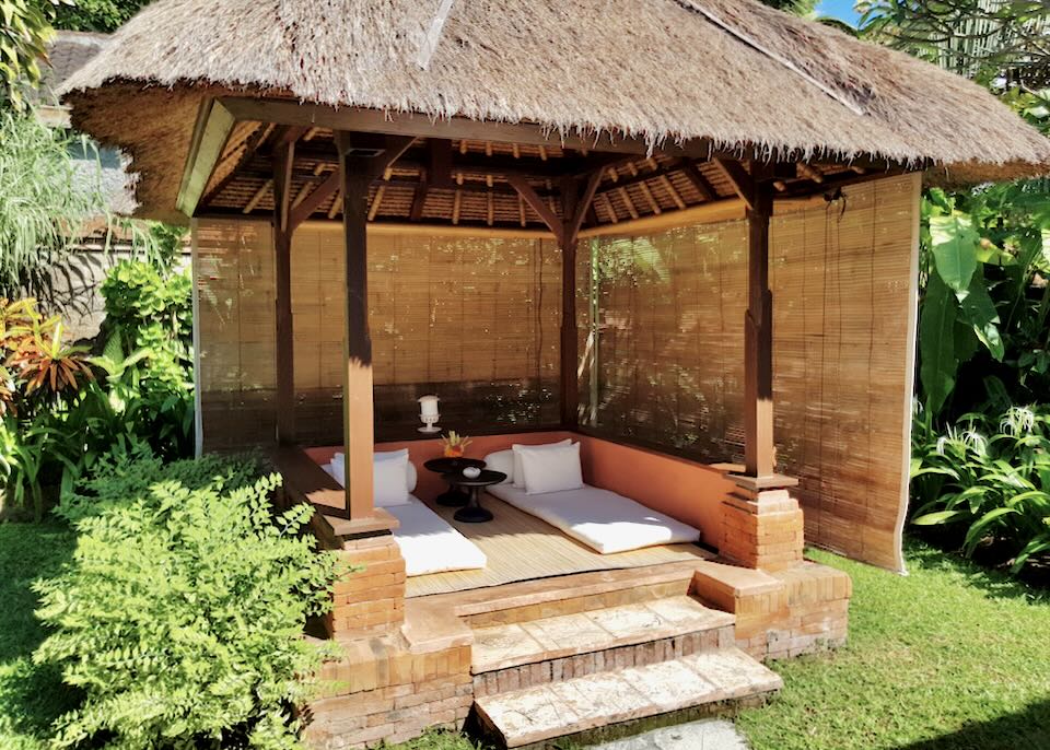 Two mattresses lay in a thatched-roof gazebo.