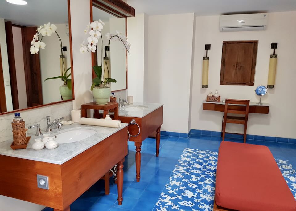 two wood sinks with white marble tops sit on a royal blue tile floor.