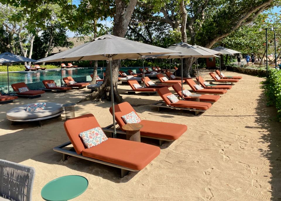 A row of orange lounge chairs face the sun.