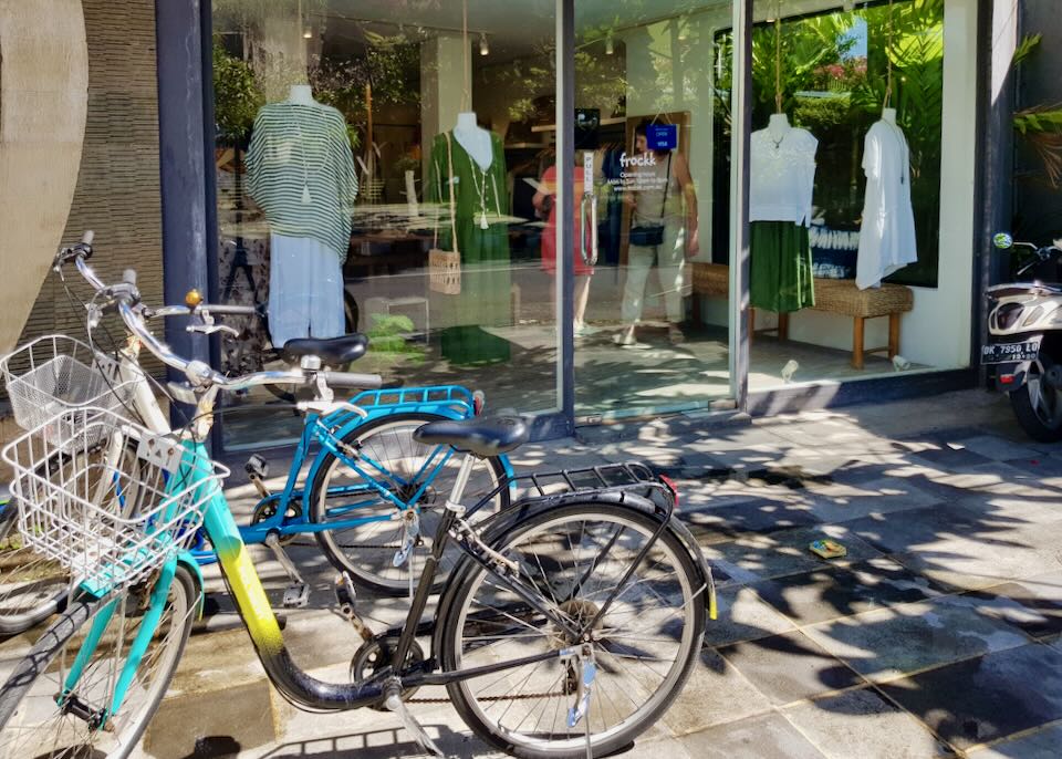 Bikes park in front of a clothing store.