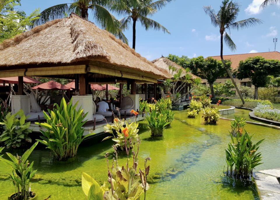 Light green ponds surround a thatched-roof restaurant.