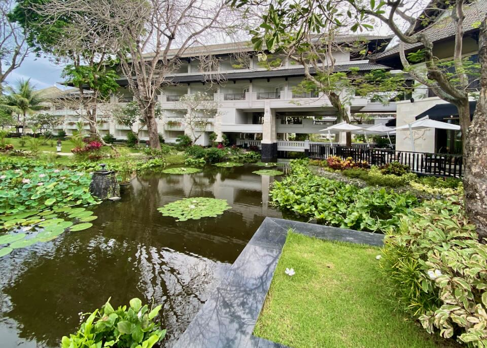 The outside of the hotel rooms with balconies overlook a pond and garden.