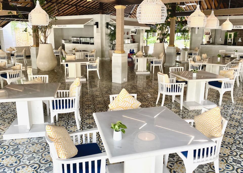 Under a thatched room sit dozens of white tables and chairs at Jimbaran Garden restaurant.