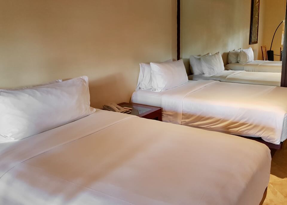 Two twin beds with white sheets sit in a room.