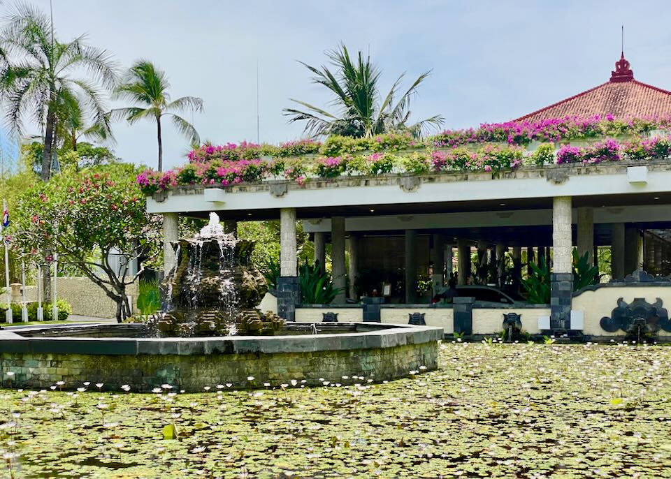 A large fountain sits in a lily pond.