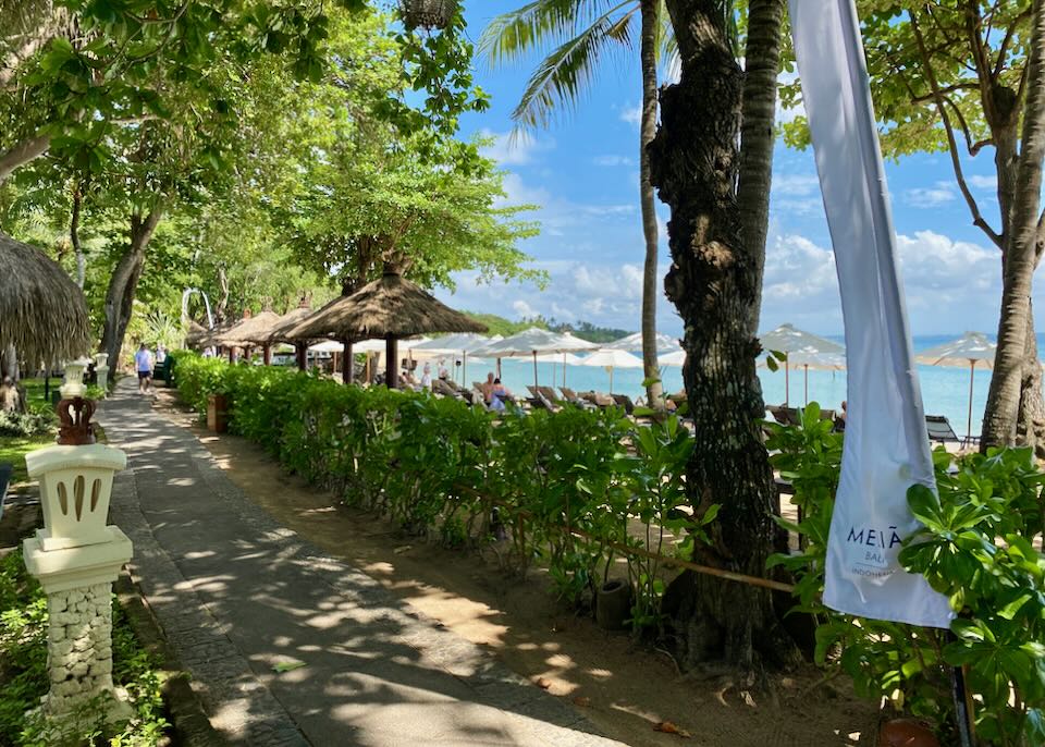 A paved shaded beachside path hugs the beach.