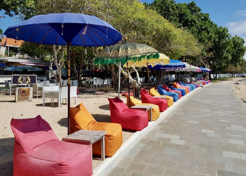 Colorful bean bag chairs line the beachside path.