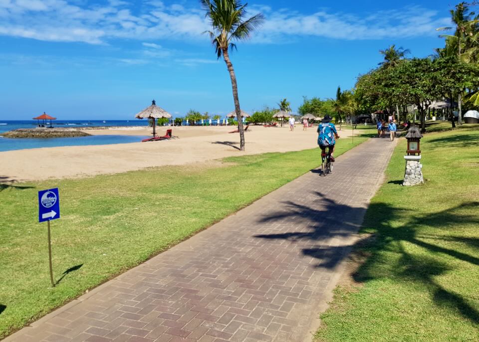 A man on a bike rides the beachside path.