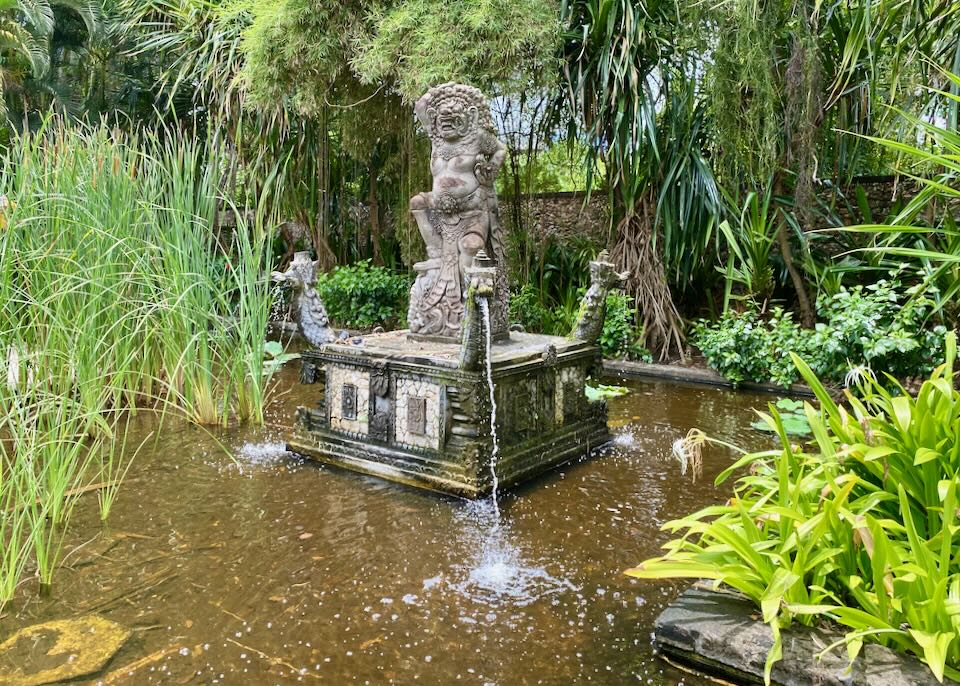 A sculpture in a pond has dragons spitting water.