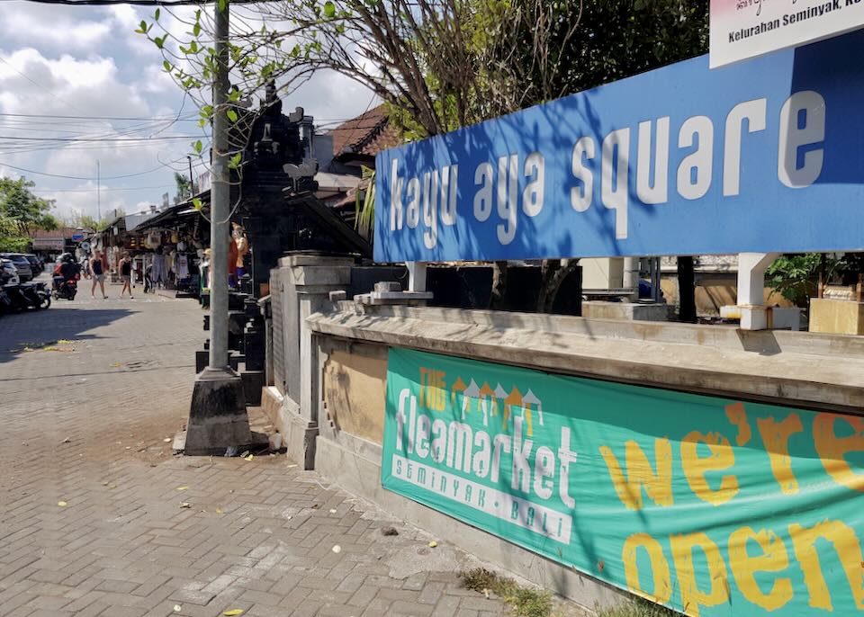 A big blue sign for Kayu Aya Square hangs on a railing.