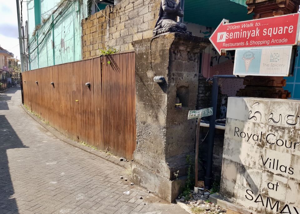 A red sign with an arrow pointing down a narrow alley says, "Seminyak Square."