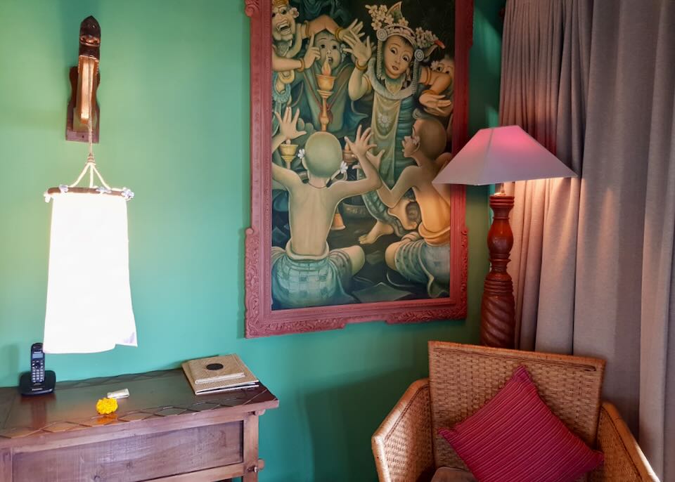 A painting in a red frame is hung on a green painted wall.