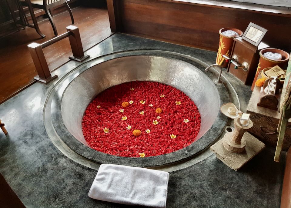 A grey tub is filled with bright red flower petals.