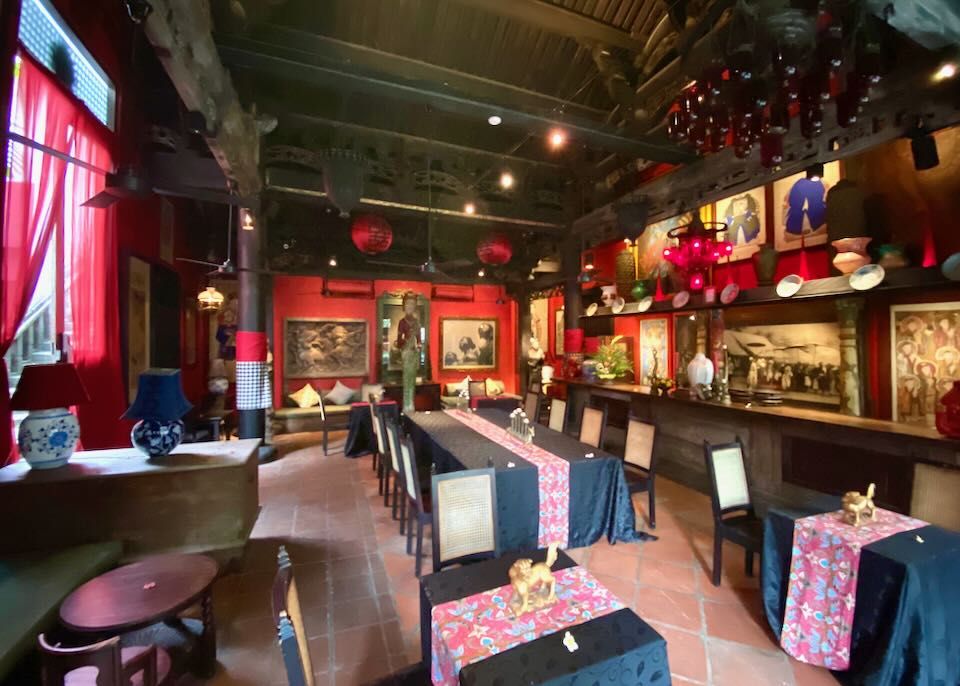 A dark restaurant with black table clothes and red painted walls.