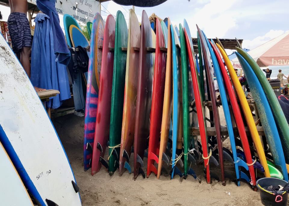 Surfboards stand in a row on the sand.