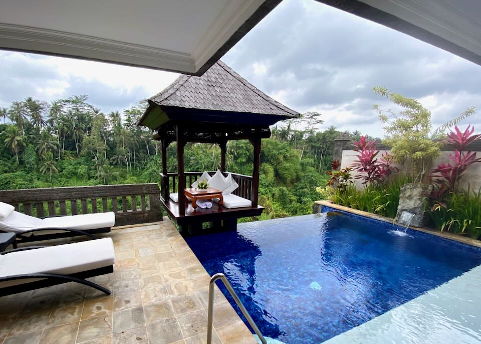 A cobalt blue pool next to lounge chairs and a gazebo.