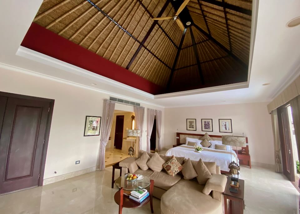 A wide view of a hotel room with a high thatched roof ceiling.