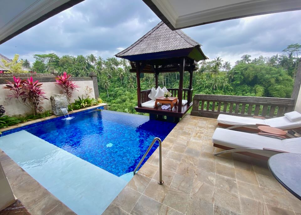 A small private infinity pool sits next to a gazebo and lounge chairs on a balcony.
