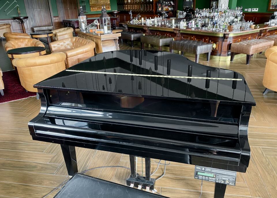 A grand piano sits in front of a bar.