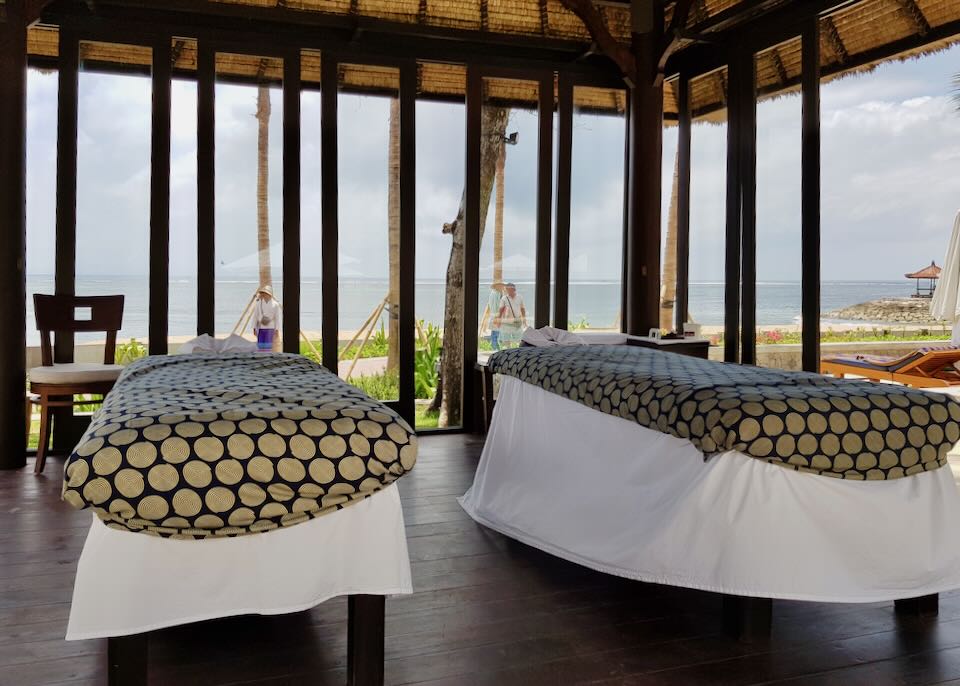 Two massage tables under a thatched-roof cabana.