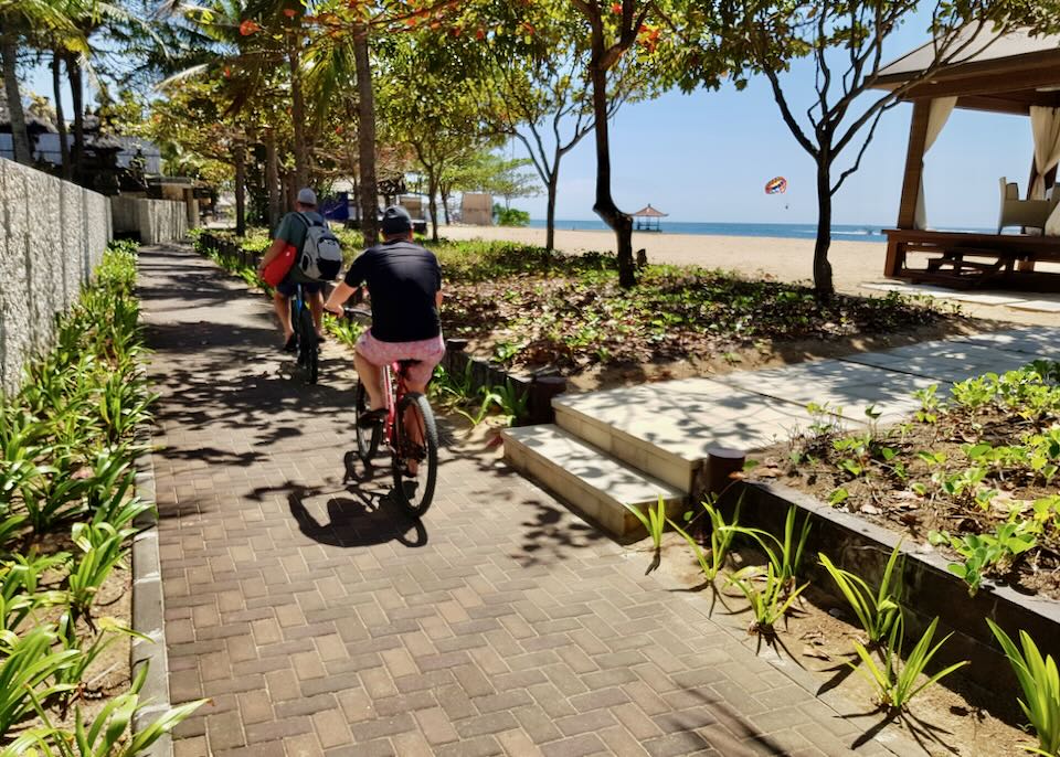 People ride bikes on a beachside path.