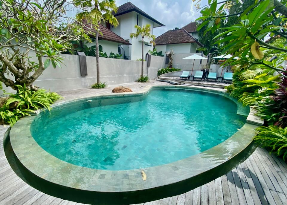 A round swimming pool in a small yard with a deck.