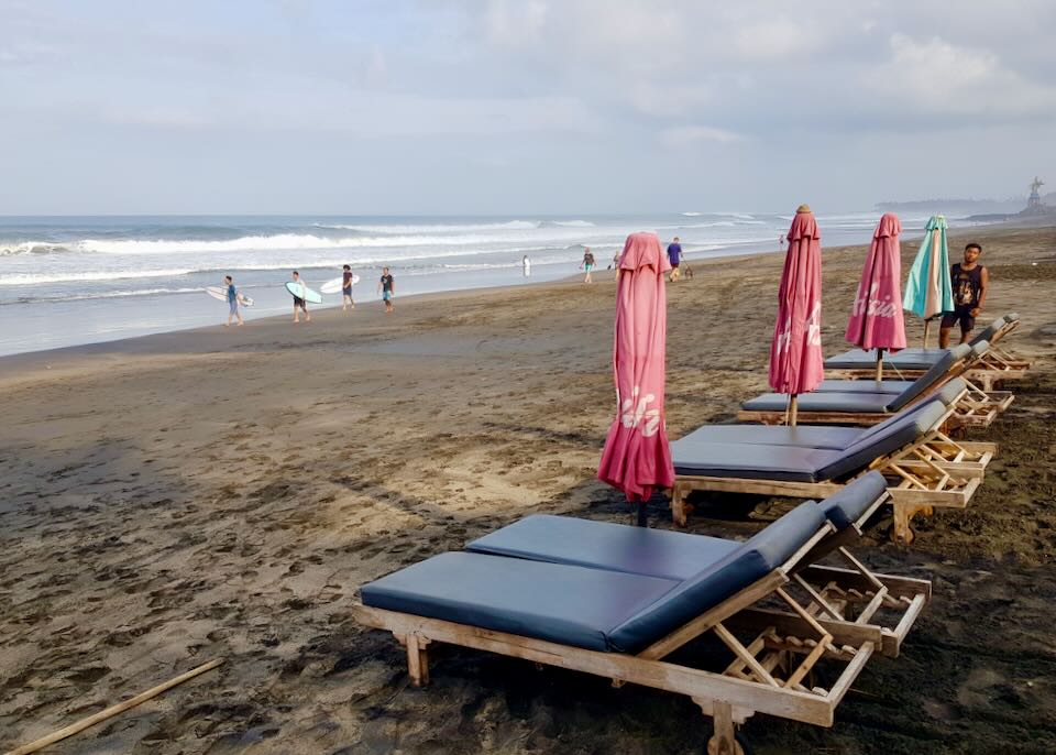Cushioned lounge chairs sit on the beach.