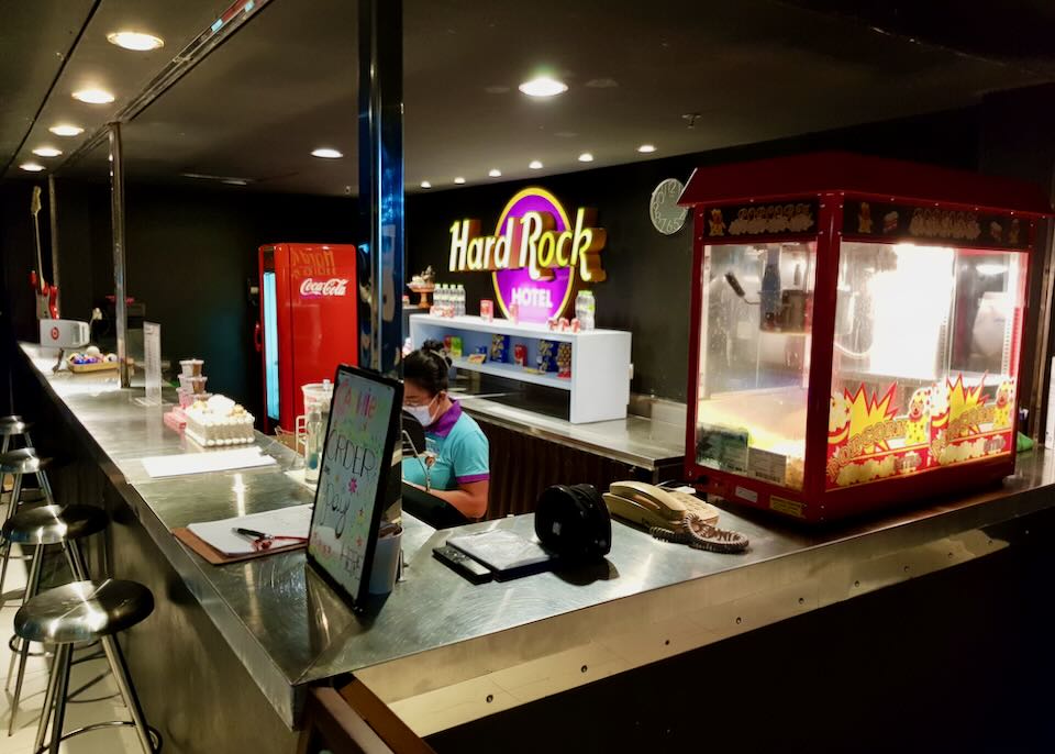 A woman stands behind a counter waiting for popcorn orders.
