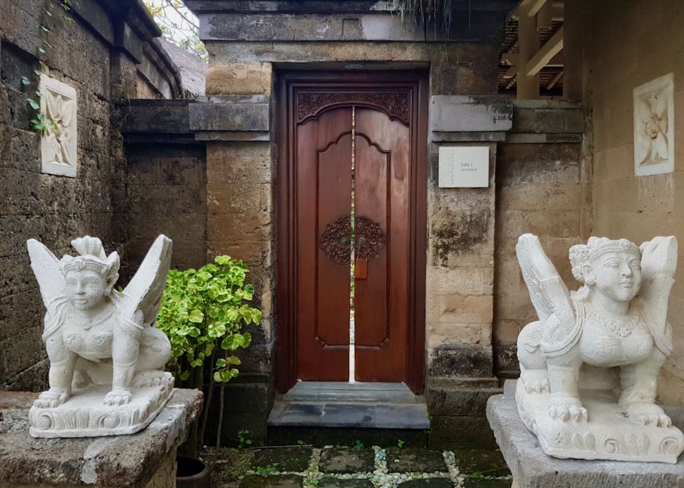 Two sculptures sit in front a two doors.