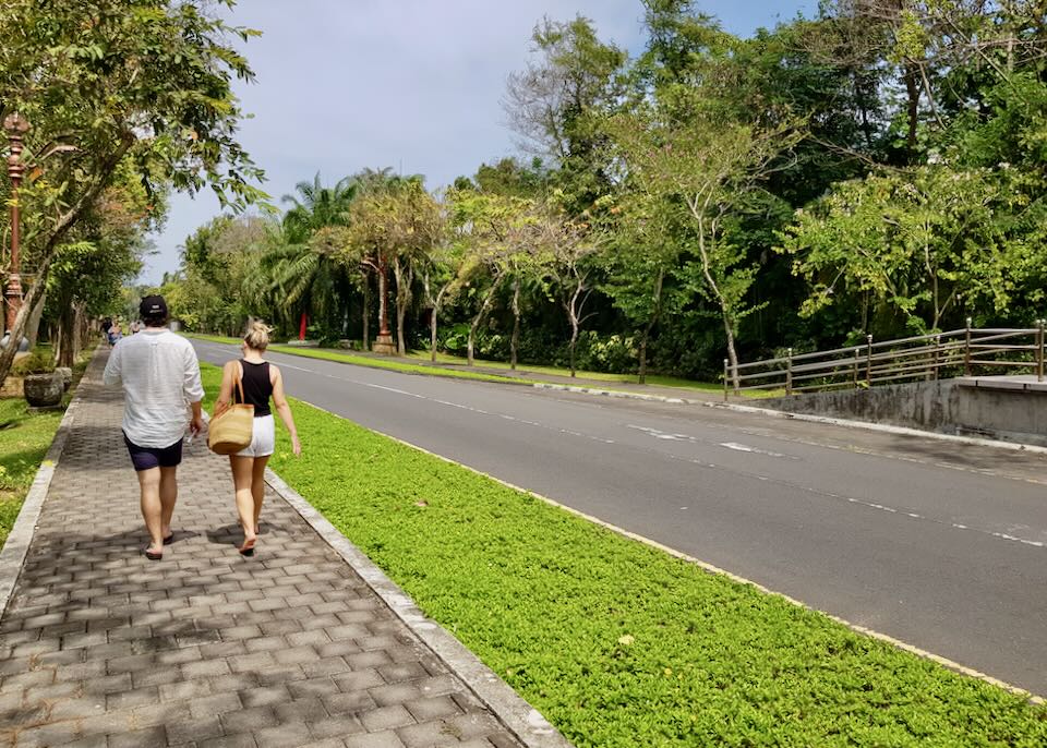 A couple walks on a sidewalk.