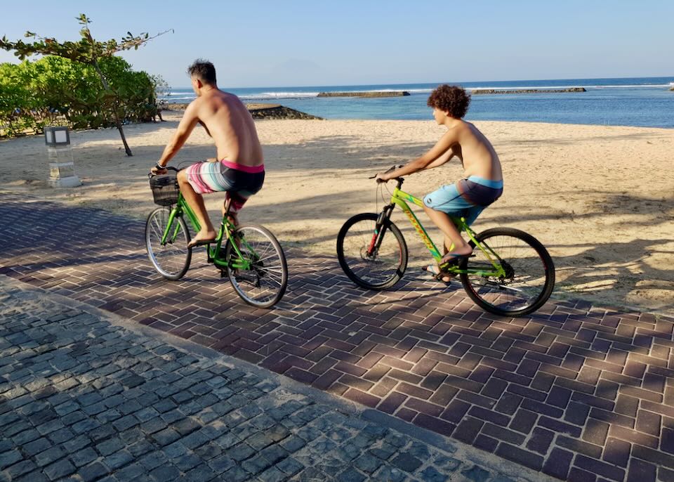 Two men ride bikes on a path.