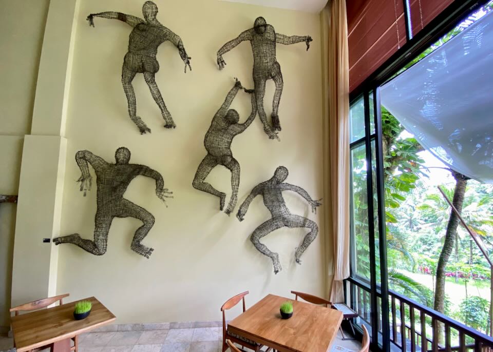 Wire sculptures of people dancing hang on the wall.