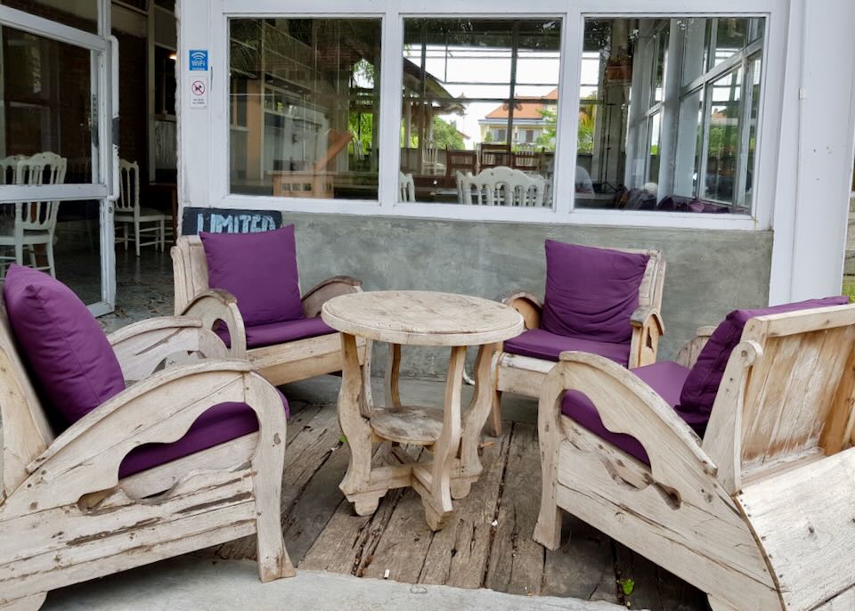 Four wood chairs sit around a table outside a restaurant.